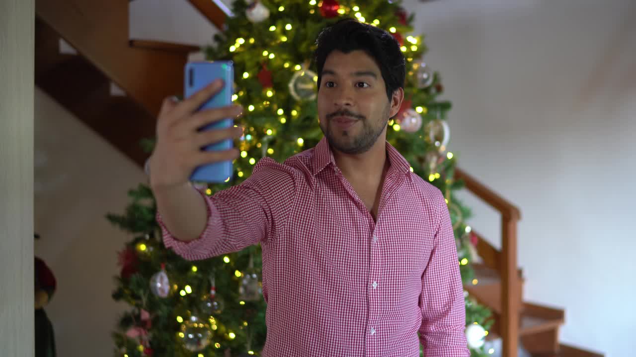 一名男子正在用智能手机进行视频通话，画面上是圣诞树视频下载