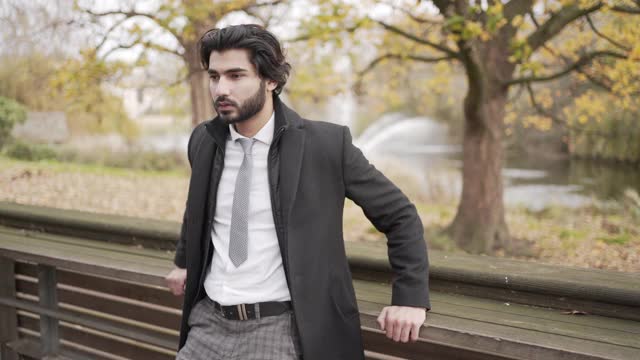 一个聪明的年轻人在公园里穿着一件外套式的夹克视频下载