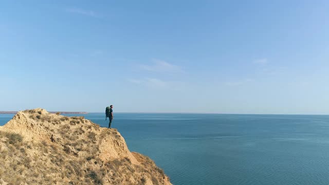 背包的旅行者站在山顶的海景背景视频素材