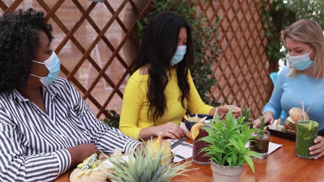 年轻的多种族女孩戴着外科口罩一起享受早午餐——冠状病毒的生活方式视频素材