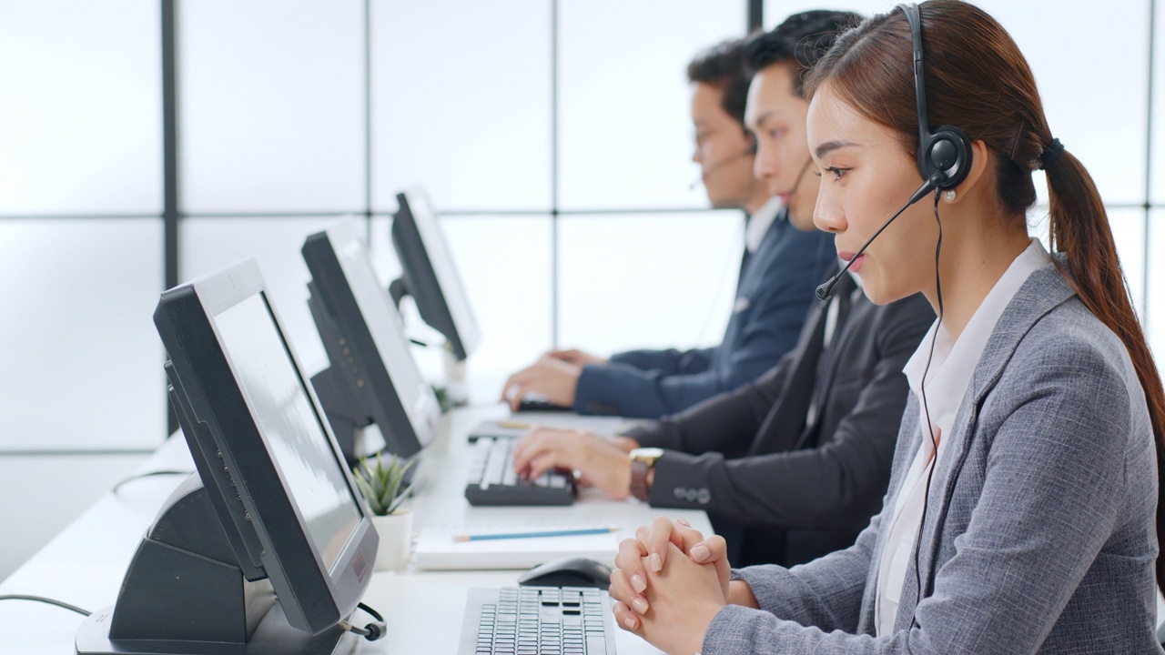 亚洲呼叫中心团队，客户服务，电话销售穿着正式的西装，戴着耳机或在现代办公室与客户交谈视频素材