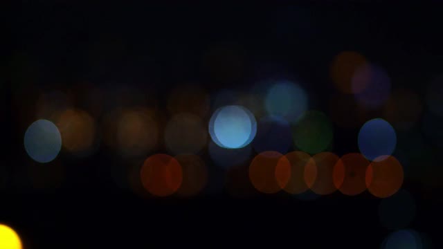 夜景在黑暗模糊的背景下，散焦的夜晚交通灯，玻璃状的圆形视频素材