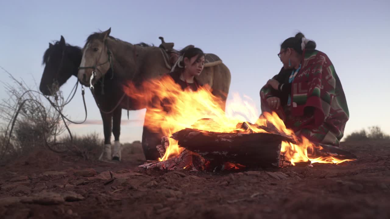 在亚利桑那州的纪念碑谷，纳瓦霍兄弟们围着一堆小篝火和马视频素材