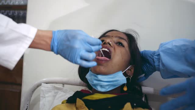 某冠状病毒医院病床上的患者covid-19病毒检测呈阳性——青少年女孩用棉签从舌、喉和鼻子上交换样本进行rtpcr检测视频下载