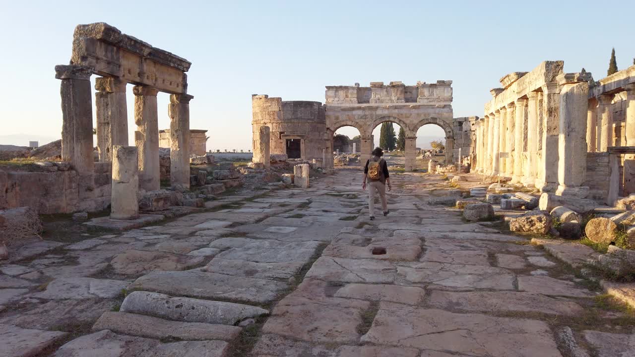 一名摄影游客正在向位于棉花堡希拉波利斯的古遗址中的Frontinus门走去视频素材