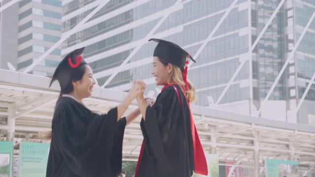 两名应届毕业生在毕业典礼上互相拥抱，表达他们的喜悦。视频素材