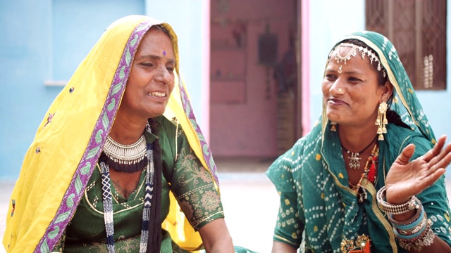 两个女人穿着鲜艳华丽的传统服装和珠宝- Ghagra Choli坐在他们的房子外面讲话，有乐趣，好玩，自以为是，淘气视频下载