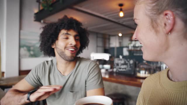 一个快乐的男人在咖啡馆喝咖啡的时候和她的女性朋友分享这个消息视频下载