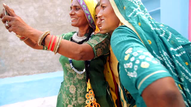 幸福微笑的家庭女性在可爱的美丽的传统印度织物衣服珠宝为一个特殊的场合传统节日排灯节拍组自拍照片在手机相机制作视频视频下载