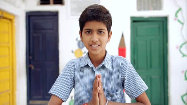 一个男孩问候与合十礼的特写，因为他加入他的双手在祈祷的位置视频素材