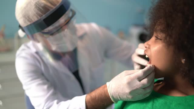 牙医坐在牙医椅上检查孩子的牙齿视频素材