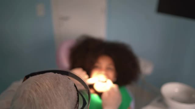 牙医坐在牙医椅上检查孩子的牙齿视频素材