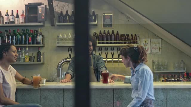 微笑的酒保在啤酒厂酒吧与顾客交谈视频下载