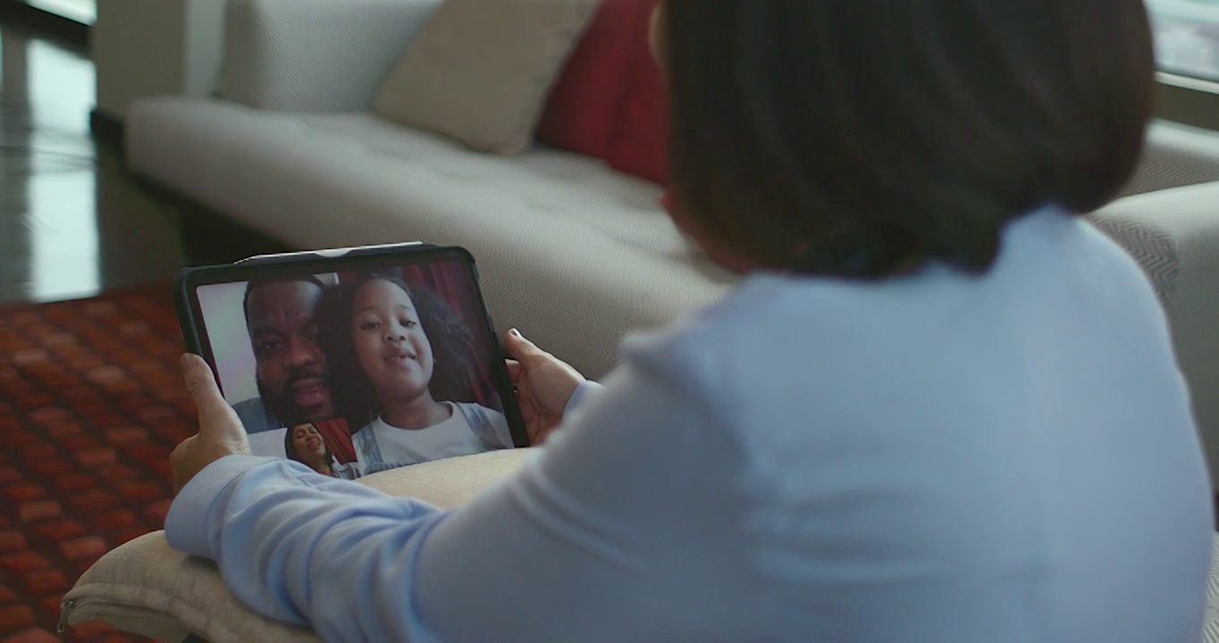 在每个人都必须适应新冠肺炎疫情的时候，一位母亲正在用平板电脑与黑人父女交谈，传达一种新的正常生活方式。视频下载