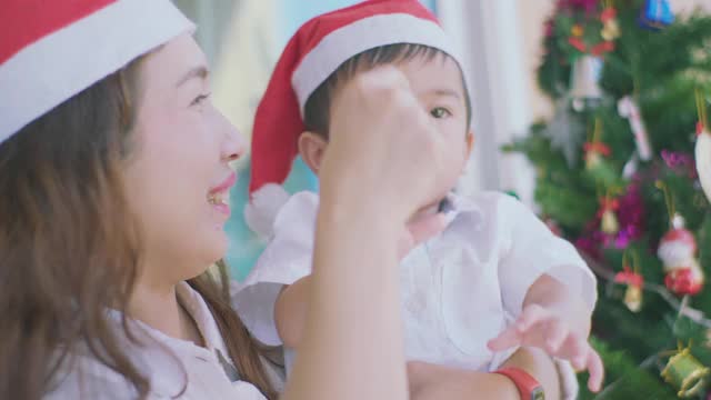 可爱的小男孩和妈妈看着圣诞树，寻找礼物。视频素材