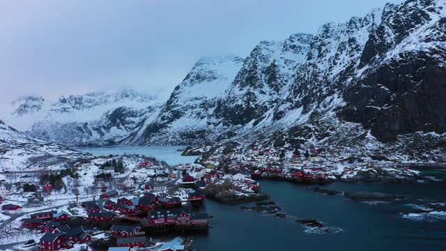 渔村A、Rorbu、海和山的冬天。Moskenes,罗弗敦群岛。挪威的风景。鸟瞰图。无人机向后和向上飞行视频素材