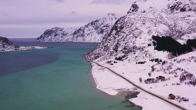 冬天的路，弗拉格斯塔德花粉和山脉。多云的天空。挪威罗浮敦群岛的Flakstadoya。鸟瞰图。无人机横着飞，向上倾斜视频素材