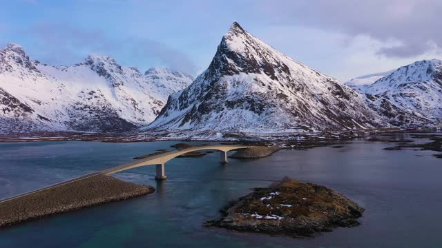 弗雷德旺悬臂桥，汽车和沃兰斯坦德山在冬季日落。Flakstadoya，罗浮敦群岛，挪威风景。鸟瞰图。无人机向后和向下飞行视频素材