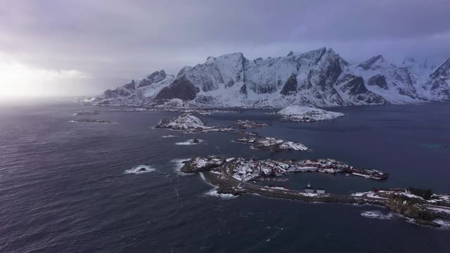 哈姆诺伊村，公路和山脉在冬天。挪威海和暴风雨的天空。摩斯基尼，罗浮敦群岛，挪威风景。鸟瞰图。无人机向前飞，向上倾斜。揭示拍摄视频素材