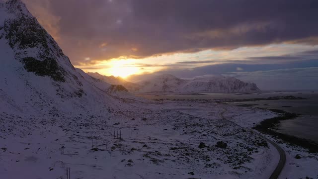 冬季日落时的路、海、岸、山。挪威罗浮敦群岛的Flakstadoya。鸟瞰图。无人机横向向上飞行视频素材