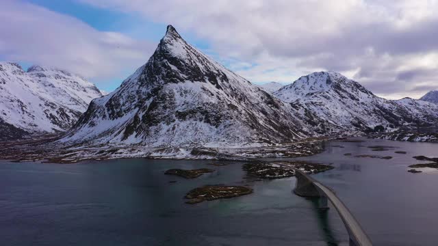 弗雷德旺桥，汽车和沃兰斯坦德山的冬天。Flakstadoya，罗浮敦群岛，挪威风景。鸟瞰图。无人机向后和向上飞行视频素材