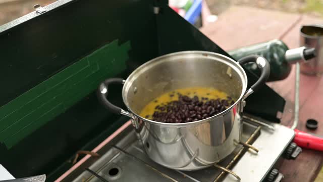 白种人的手搅拌锅的食物在丙烷野营炉上烹饪视频下载