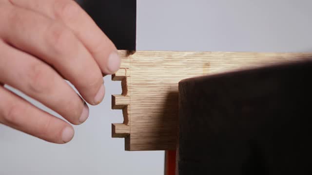 关闭了。一名男子用日本手锯在橡木板上雕刻燕尾榫。手工木工。木工工具的声音视频下载