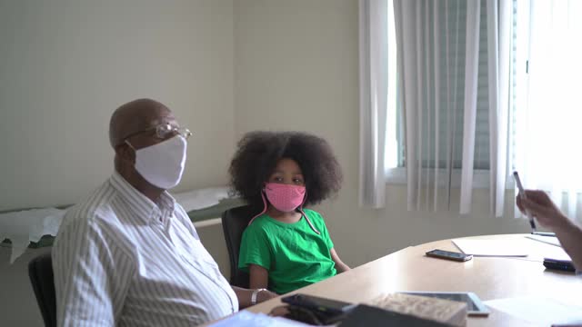 成熟的医生与老病人和他的孙女在医生的预约视频素材