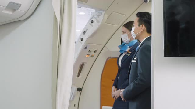 两名友好的空姐和空姐站在飞机门附近欢迎乘客进入飞机视频素材