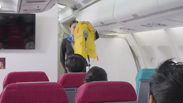 亚洲空乘人员在飞机起飞前向乘客演示安全程序。视频素材