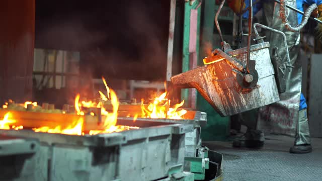 在铸造厂，操作人员将熔化的金属从熔炉中挤出，然后浇注到钢包中视频素材