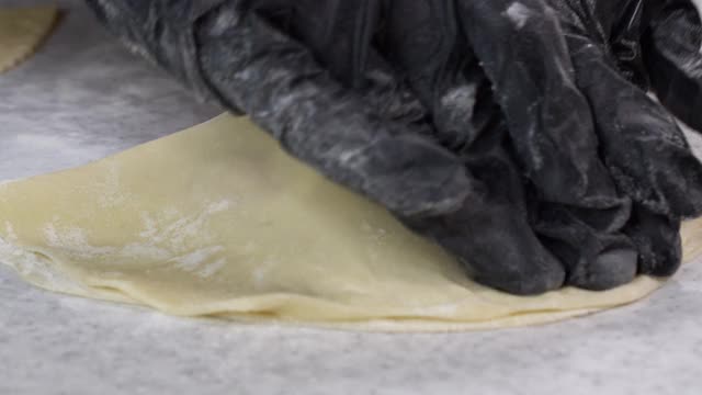 手在黑手套面包店厨师在面团上应用面粉的特写镜头，孤立的背景4k镜头。视频素材