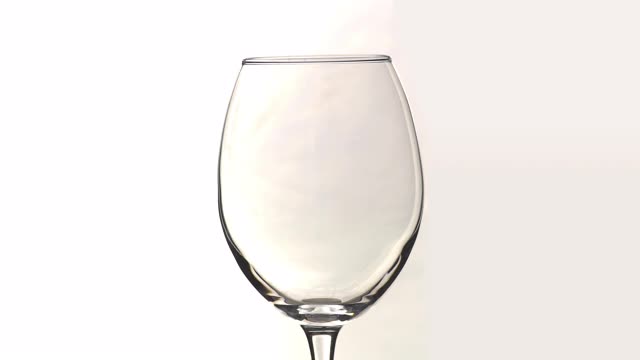 年轻的白葡萄酒倒入玻璃杯的慢动作孤立的近距离视频下载