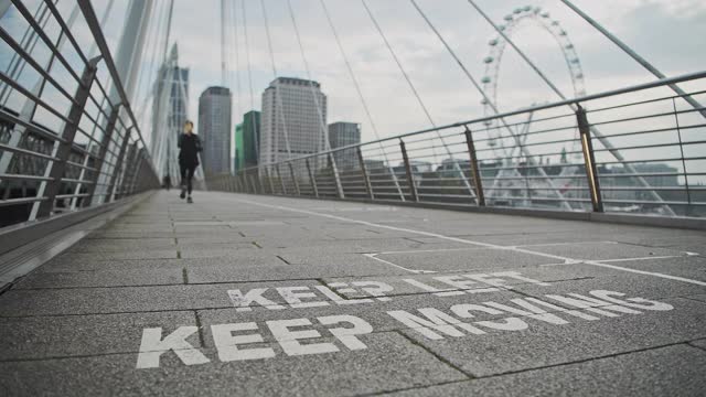 在伦敦市中心南岸的Jubilee Bridges，新冠肺炎信息标志鼓励社交距离，显示在英国和欧洲，人们必须遵守2米社交距离的规则视频下载