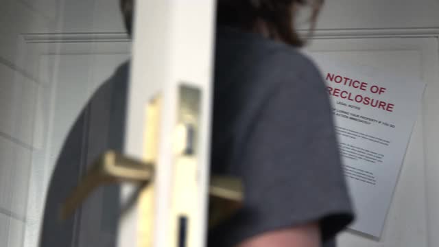 女性的白种人的手在一户人家的前门挂着一张取消抵押品赎回权的通知视频下载