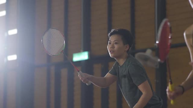 亚洲华人羽毛球运动员在羽毛球场上进行比赛视频素材