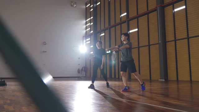 亚洲华人羽毛球运动员在羽毛球场上进行比赛视频素材
