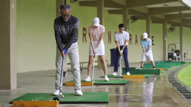 亚洲华人高尔夫球手在高尔夫球练习场打球视频下载