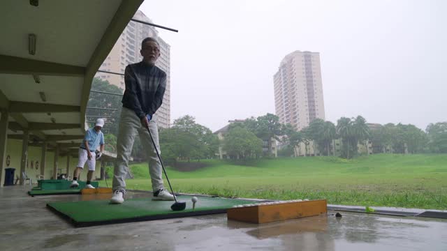 亚洲华人成熟男子高尔夫球手在高尔夫练习场打球视频下载