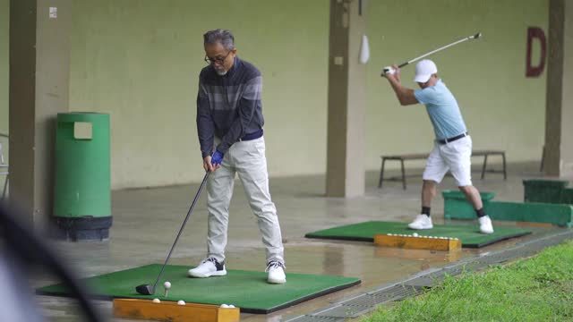 亚洲华人成熟男子高尔夫球手在高尔夫练习场打球视频下载