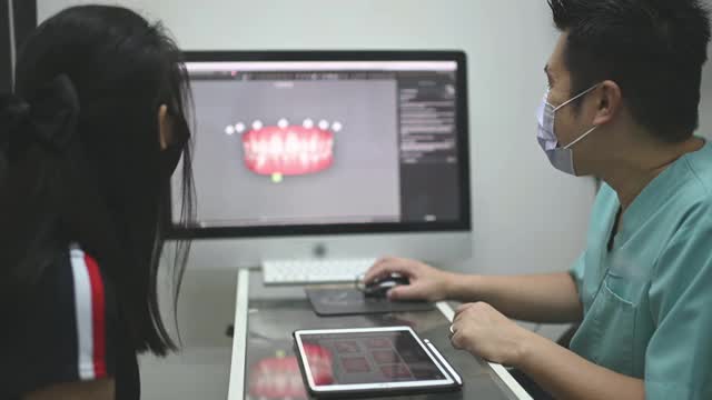 亚洲华裔男性牙医向病人解释牙齿x光片视频下载