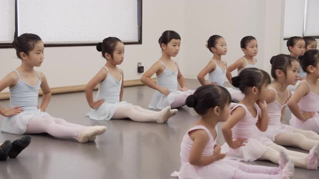 穿着紧身衣的亚洲芭蕾学生的孩子们正在工作室里并排上课视频素材