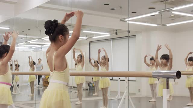 穿着紧身衣的亚洲芭蕾学生的孩子们正在工作室里并排上课视频下载