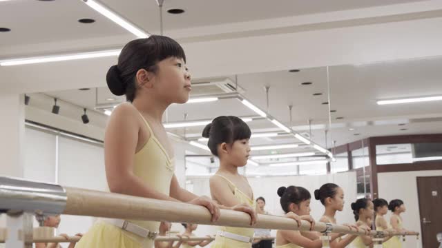 穿着紧身衣的亚洲芭蕾学生的孩子们正在工作室里并排上课视频素材