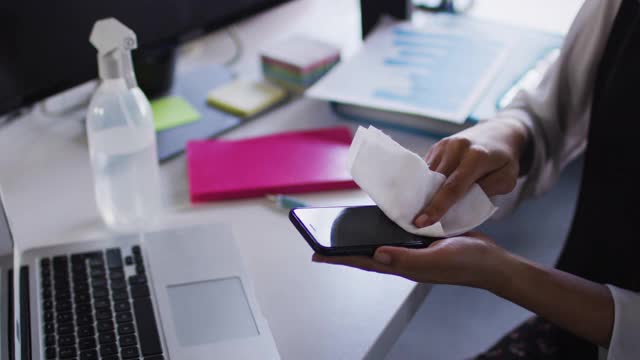 女性在现代办公室用纸巾清洁智能手机视频下载