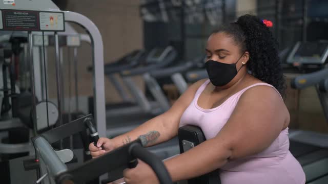 一名年轻女子戴着面具在健身房锻炼的肖像视频素材