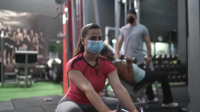 年轻女子在健身房训练，戴着口罩视频素材