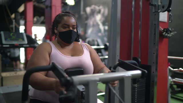 年轻女子在健身房用口罩做运动视频下载
