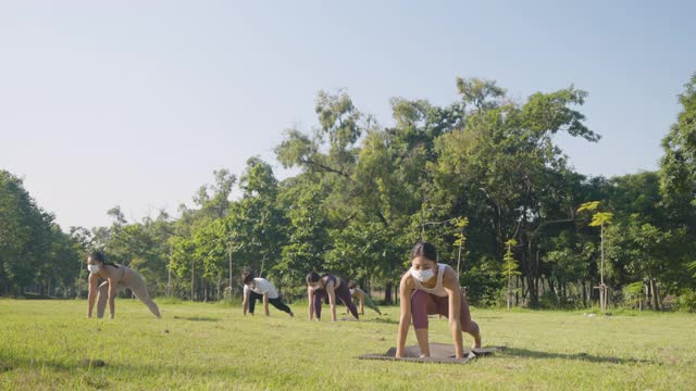 不同年龄层的人戴着医用防护口罩在户外做瑜伽姿势练习——隔离期间或隔离后的生活理念，冠状病毒防护措施视频素材