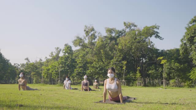 不同年龄层的人戴着医用防护口罩在户外做瑜伽姿势练习——隔离期间或隔离后的生活理念，冠状病毒防护措施视频素材